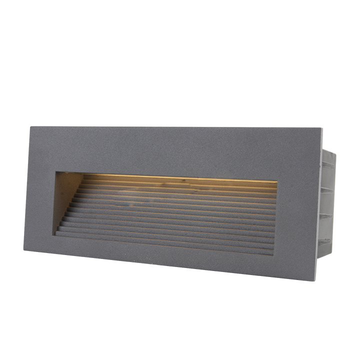 Close-up of a modern LED step light installed on an outdoor stone step, casting a warm downward beam for safety